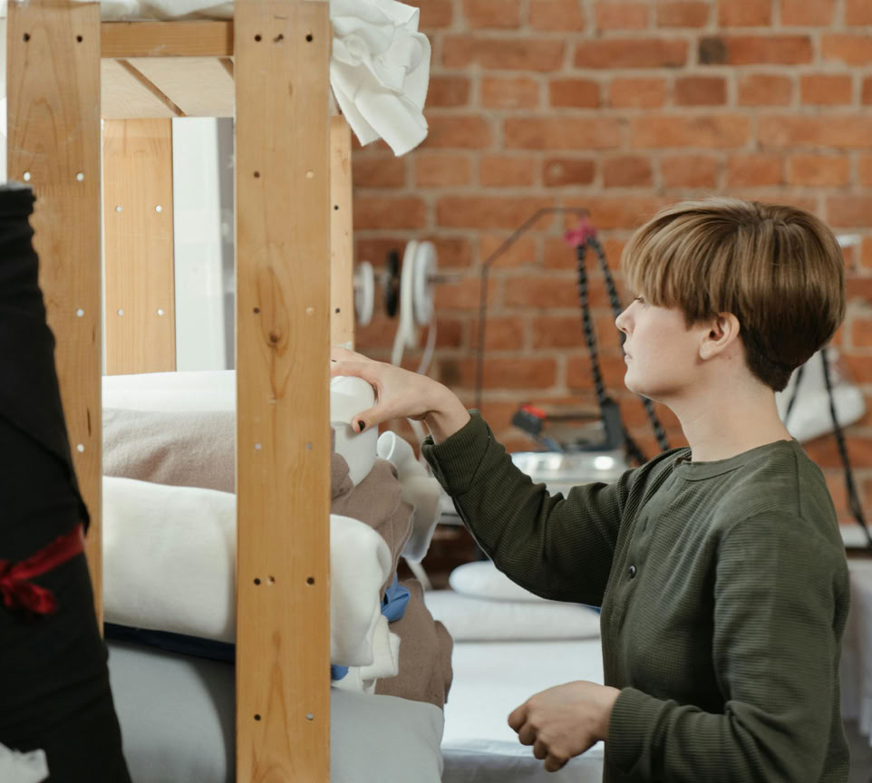 Garçon En Veste Verte Assis Sur Un Lit Blanc